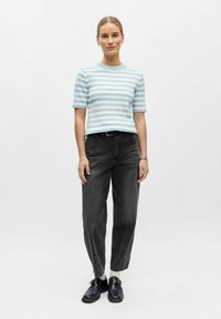 Pull à manches courtes rayé bleu clair et blanc, associé à un jean noir et des chaussures noires. Design simple avec une coupe décontractée.