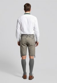 Tenue masculine comprenant une chemise blanche avec col vert, un short gris et des chaussettes gris mi-mollet, complétée par des chaussures brunes et des détails de design subtils.