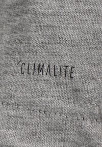 Primo piano di un tessuto grigio con una superficie testurizzata e cuciture visibili, con un logo in rilievo "CLIMATLITE" in nero.