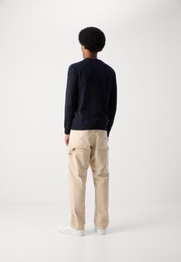 Navy long-sleeve shirt, beige cargo pants, white sneakers. Simple design, soft texture, relaxed fit. Minimalist style with no visible branding.