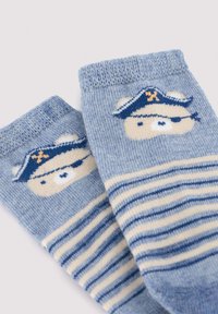 Calcetines de bebé azules y beige con rayas horizontales y una cara de oso que lleva un sombrero de pirata y un parche en el ojo en la zona del tobillo.
