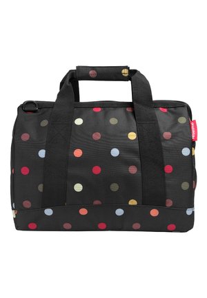Bolsa de viaje de tela negra con lunares de colores, dos asas negras y una etiqueta roja en el lateral.