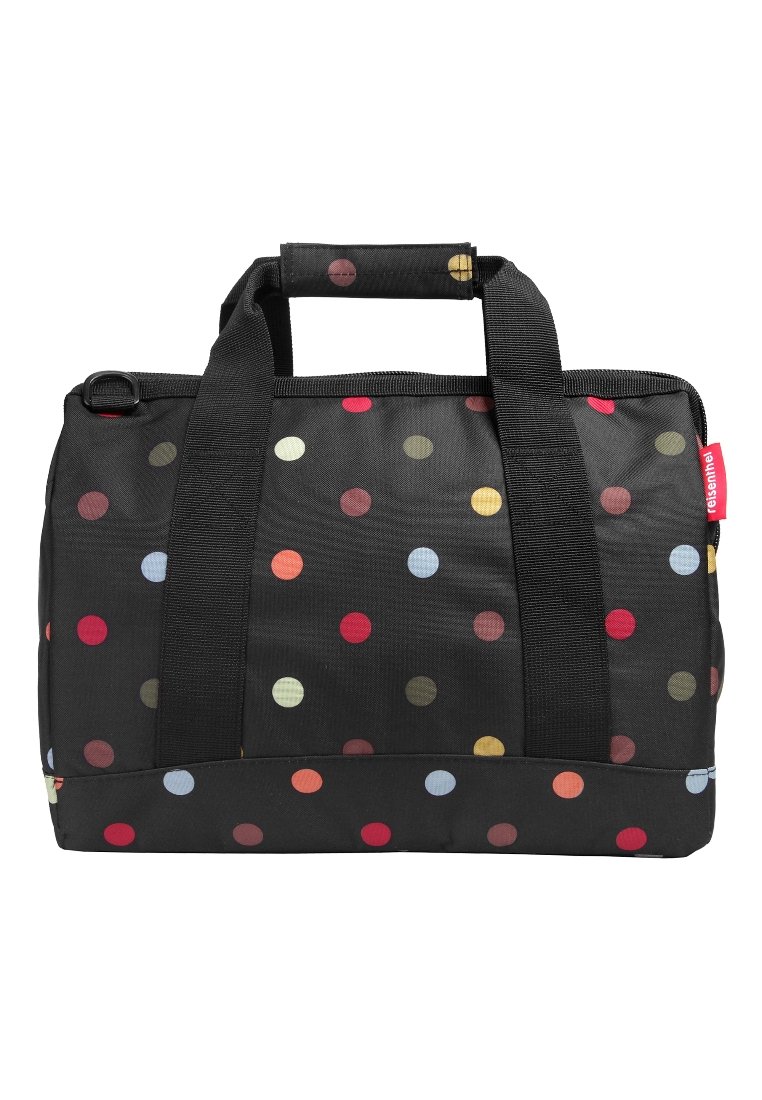 Bolsa de viaje de tela negra con lunares de colores, dos asas negras y una etiqueta roja en el lateral.