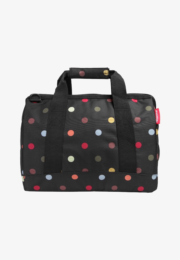 Black fabric duffel bag with colorful polka dots, two black handles, and a red tag on the side.