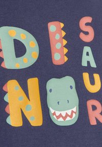 Kék anyag, amelyen színes betűk írják a "DINOSAUR" szót egy rajzfilmes dinoszaurusz fejével. A betűk vastagok, játékosak és texturáltak.