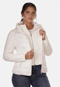 Giacca a vento bianca con cappuccio rimovibile, zip frontale e due tasche laterali, caratterizzata da una texture trapuntata e un tessuto liscio.