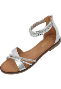 Silberne flache Sandale mit geflochtenem Knöchelriemen, strukturierten metallischen Akzenten und weichem, hellem Innenfutter. Offene Zehenkonstruktion mit minimaler Detailgestaltung.