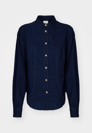 Cămașă din denim albastru închis, cu guler, mâneci lungi și închidere cu nasturi. Detalii de cusătură distincte și nasturi rotunzi sunt vizibile.