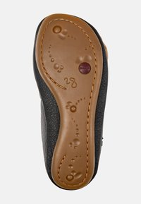 Suela de zapato de cuero negro con base de goma marrón, que presenta patrones texturizados y un diseño curvado. Incluye un logo en relieve y detalles de costura.