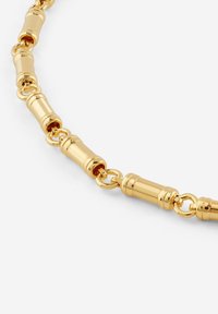 Gouden ketting met cilinderachtige schakels afgewisseld met ronde verbindingsstukken, een glad oppervlak en een reflecterende textuur.