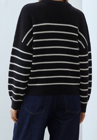 Randig svart- och vitstickad tröja med avslappnad passform, ribbat mönster och sänkta axlar. Designen har breda horisontella ränder.