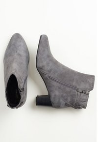 Harmaat mokkanahkasaappaat nilkkapituisilla, terävillä kärjillä ja neliskanttisella korolla. Varustettu sivuvetoketjulla ja koristeompeleilla ulkopuolella.