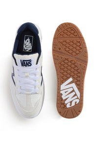 Białe sportowe buty z granatowymi akcentami. Białe sznurówki, logo na języku oraz teksturowana podeszwa z gumy o wyraźnym logo marki.