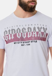 Weißes Baumwoll-T-Shirt mit grafischem Print in Rot- und Grautönen, Text mit der Aufschrift "NY CITY STREET STYLE" und dem Gründungsjahr 1996.