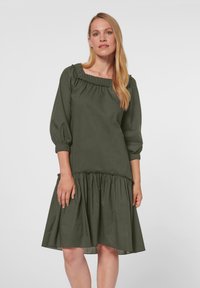 Grünes knielanges Kleid mit gerafftem Ausschnitt und gepufften 3/4-Ärmeln. Es hat einen gerafften Saum und ein strukturiertes Gewebe für zusätzliche Details.