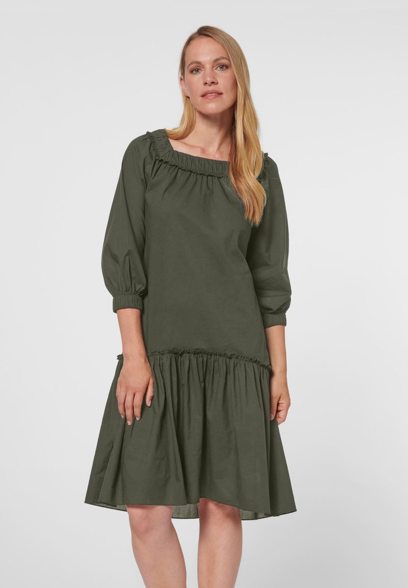 Grünes knielanges Kleid mit gerafftem Ausschnitt und gepufften 3/4-Ärmeln. Es hat einen gerafften Saum und ein strukturiertes Gewebe für zusätzliche Details.