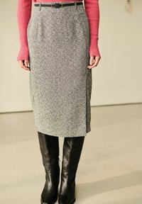Grå tekstureret blyantskirt med en sideslids, parret med knæhøje sorte læderstøvler. Toppen har lyserøde ribbede lange ærmer.