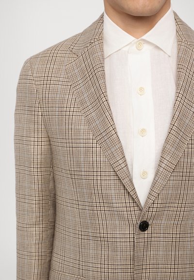 Beige karierter Blazer mit einem einzelnen schwarzen Knopf, ausgestattet mit taillierten Revers und einem weißen Hemd darunter. Strukturiertes Stoffmuster.
