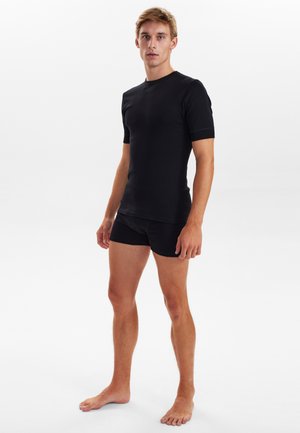 Sort fitted t-shirt med korte ærmer, lavet af glat stof. Sæt sammen med sorte shorts, der fremhæver en strømlinet silhuet.