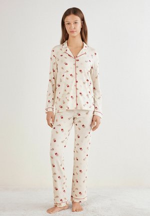 Blomstermønstrede bomuldspyjamas i creme med røde accenter; har en knap-op top og lange bukser med elastisk talje.