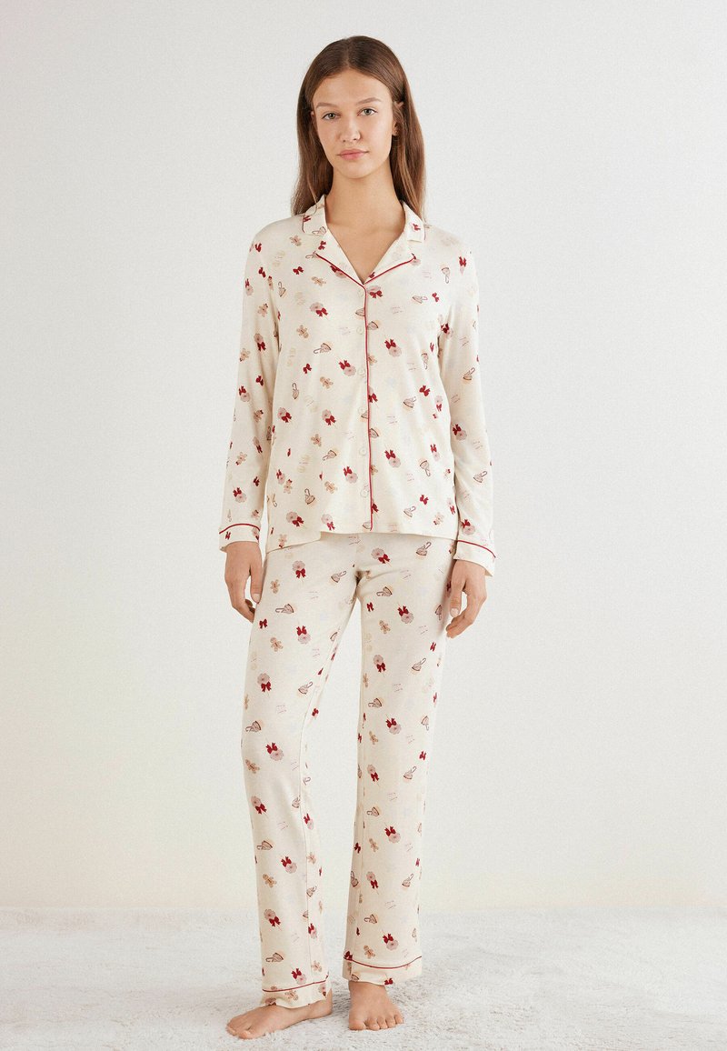 Bawełniane piżamy w kwiatowy wzór w odcieniu kremowym z czerwonymi akcentami; zawierają koszulę zapinaną na guziki oraz długie spodnie z elastycznym paskiem w talii.