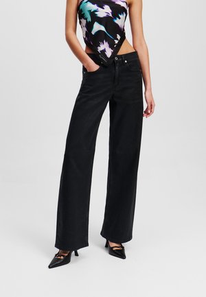 Pantalones vaqueros anchos negros de denim, con una cintura alta, diseño de cinco bolsillos y un ligero desvanecimiento. Combinándolos con una blusa de patrón colorido.
