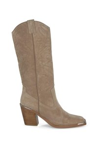 Bota de cowboy de ante beige con punta afilada, costuras decorativas en el eje y un tacón cuadrado con un acento metálico en la punta.