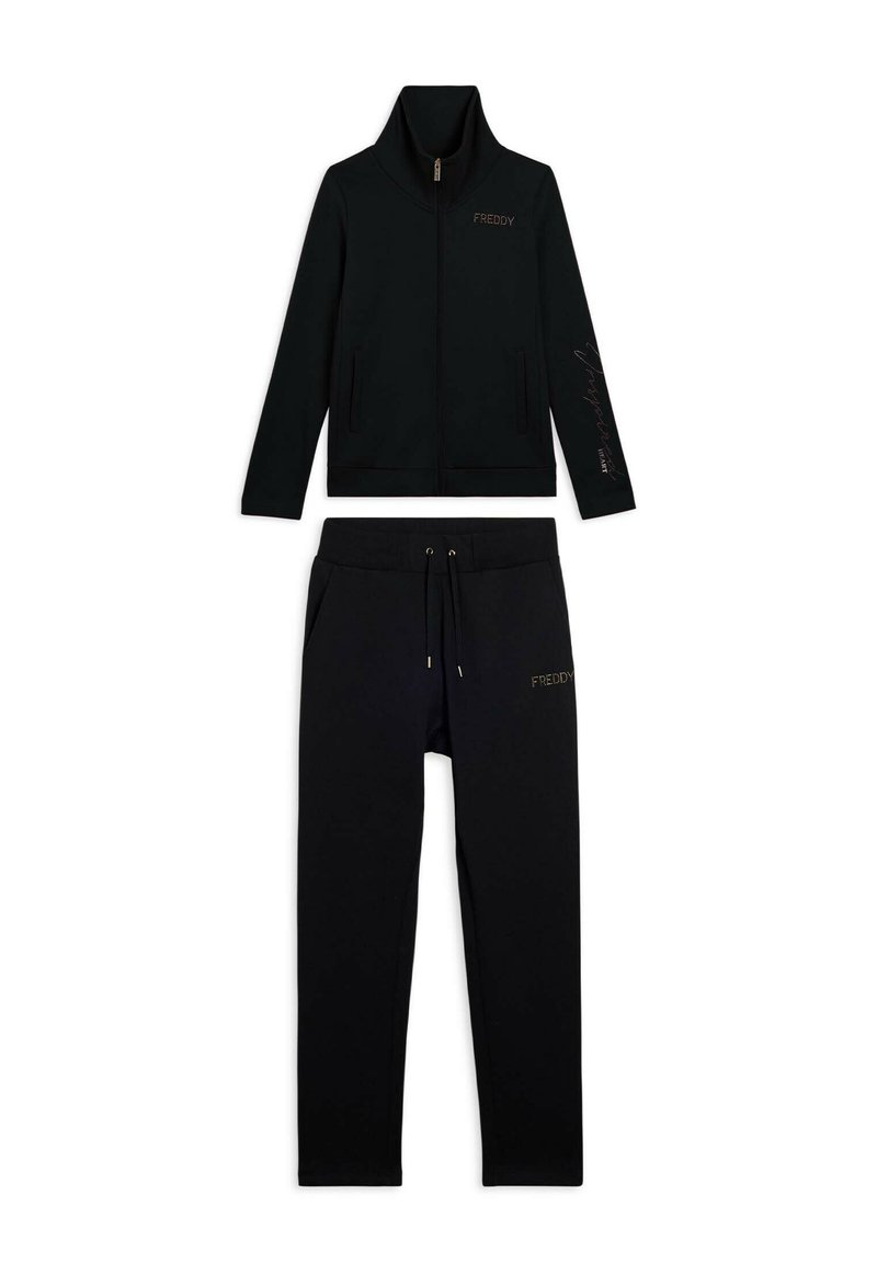 Chaqueta negra con cremallera y cuello alto, y pantalones a juego con cordones, ambos con la marca "FREDDY" en el pecho y en el muslo.