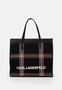 Svart tote-väska med rutigt mönster i röd och vit. Har svarta handtag i konstläder och en vit logotyp på framsidan.