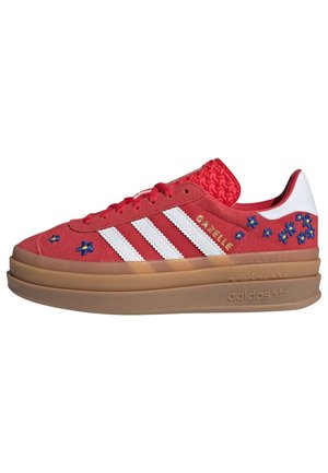 Rød Adidas Gazelle sneakers med hvide striber, blå blomsterbroderi, tekstureret tunge og tyk brun sål på hvid baggrund.