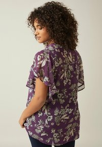 Lila Bluse mit floralem Muster, kurzen Rüschenärmeln, leichtem Stoff und lockerer Passform. Verfügt über einen subtilen Glanz und einen abgerundeten Saum.