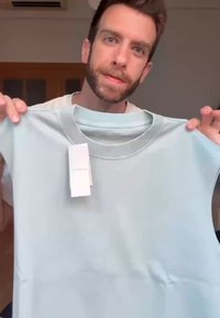 Light blue short-sleeve shirt made of smooth fabric, featuring a round neckline and a white price tag attached near the collar.