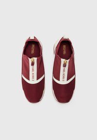Sneaker slip-on rossi in rete con accenti bianchi, dotate di una chiusura con zip dorata sulla parte anteriore e dettaglio del logo sul lato. Suola piatta in gomma.