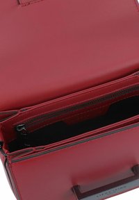 Red leather handbag with a structured design, featuring a top handle, interior zip pocket, and smooth texture.
