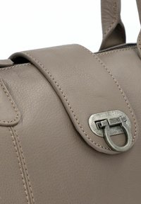 Borsa in pelle di un taupe chiaro con una superficie liscia, dotata di una chiusura rotonda argentata e cuciture a contrasto lungo il pattina.