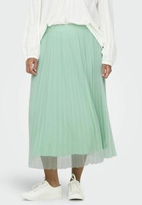 Plisovaná midi sukňa v svetlo mentolovej farbe, vyrobená z ľahkej textílie. Má elastický pás a vrstvený dizajn, skombinovaná s bielymi teniskami.