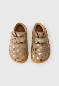 Kinderschuhe mit einem beigen Wildleder-Außenmaterial, das metallische Herzmuster in Silber, Gold und Bronze aufweist. Mit Klettverschluss und Gummisohlen.