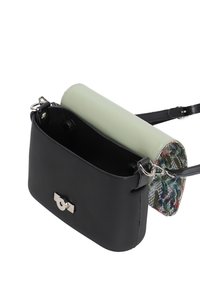 Borsa in pelle nera con un portapennelli cilindrico staccabile di colore verde chiaro. Presenta dettagli in metallo argentato, un motivo sulla parte posteriore e una sola tracolla.