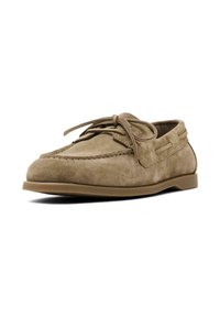 Beige suède instappers met een gewatteerde kraag, vetersluiting en een platte rubberen zool. Heeft stiksels langs de naden en een gladde textuur.