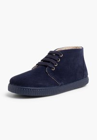 Botas chukka de ante azul navy con diseño de cordones, puntera redonda, suela de goma texturizada y forro suave. Presenta acentos de costura.