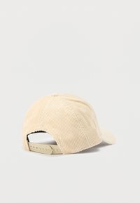 Beežist sametkangast nokamüts kõverda nokaga, reguleeritava rihma ja tekstuursete soontega. Tagantvaates paistab rihm ja kangast detail.