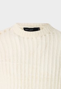 Cremefarbenes Strickpullover mit Rippstruktur, Rundhalsausschnitt und einem Etikett mit der Aufschrift "NIGHT ADDICT" im inneren Kragen.