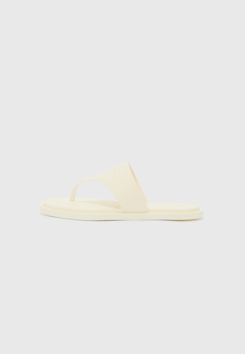 Yellow rubber flip-flop with a wide strap and a toe post. Flat sole, minimalistic design, smooth texture. Simple and functional style.