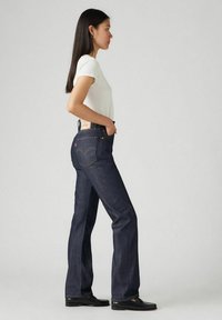 Ciemnoniebieskie dżinsy o prostym kroju, z tylnymi kieszeniami z wkładem w kształcie łuku oraz metką marki na pasku.