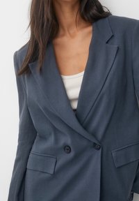 Blazer doppiopetto blu scuro realizzato in tessuto testurizzato con reverse a punta, due tasche frontali e bottoni neri.