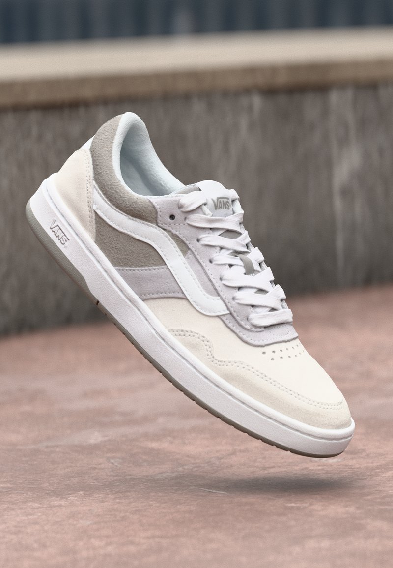 Hvide og lysegrå sneakers med overdel i læder og suede, perforeret tå og struktureret detaljering. Har hvide snørebånd og logo.