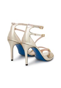 Sandali con tacco alto oro, con punta affusolata e suola blu. Presentano più cinturini con fibbie regolabili e un accentuato fiocco. Texture liscia.