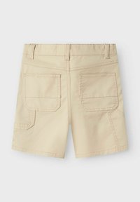 Shorts beiges à coupe droite, avec deux poches arrière et des détails de couture visibles. Fabriqués en tissu durable avec une texture lisse.