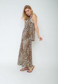 Sukienka bez rękawów w print panterki o luźnym kroju, z warstwowym designem i kontrastującymi jasnoniebieskimi akcentami. Dominują odcienie beżu i brązu.