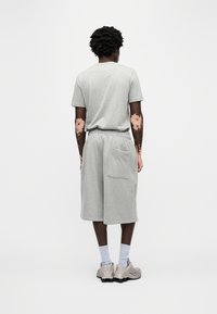 Σετ γκρι βαμβακερό t-shirt και σορτς, με ελεύθερη εφαρμογή και ελαστική μέση, εμφανιζόμενο από πίσω, με πλαϊνή τσέπη στα σορτς.